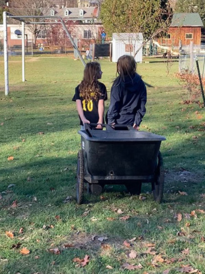 Two children pulling wheelbarrow