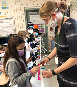 Teacher working with students in a line measuring colorful sticks
